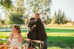 A couple reacts emotionally during their outdoor wedding reception meal.