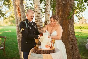 A couple poses playfully near birch trees at an outdoor wedding venue.