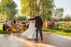 A couple shares an intimate dance moment on an outdoor wooden dance floor.