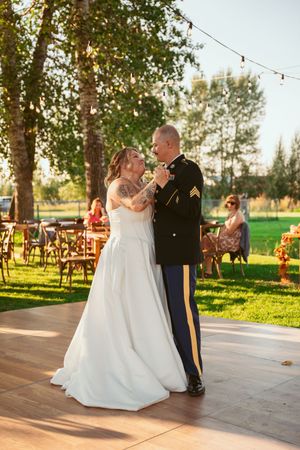 A beautiful summer wedding dance takes place on an outdoor patio surrounded by trees during golden hour.