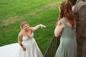 Wedding party members in sage green dresses laugh and interact during outdoor reception festivities.