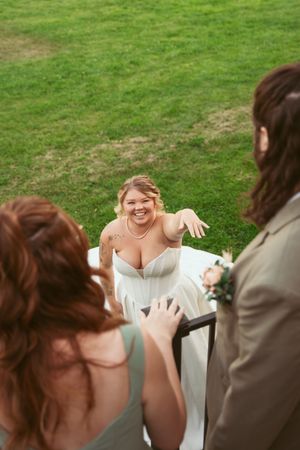 People sharing a joyful moment outdoors on a grassy lawn during a wedding celebration.