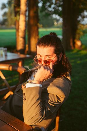 People sharing quiet sunset moments together at a wooden picnic table in a park.