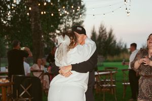 A couple sharing a romantic dance moment at sunset during an outdoor celebration.
