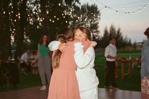 A tender dance moment at an outdoor evening reception with string lights overhead and guests in the background.