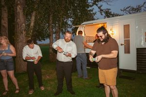 Group gathers outside on a lawn at dusk for a casual event or gathering.