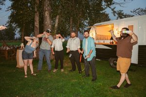 Wedding guests dance and celebrate on an outdoor patio surrounded by string lights at dusk.