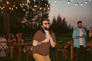 Wedding reception dance party on an outdoor deck with string lights and sunset views.