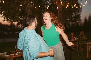 Friends dancing and celebrating together at an outdoor gathering during golden hour.