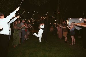 Party guests dancing in a circle under twinkling lights strung between trees at night.
