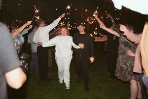 A nighttime celebration with people dancing and holding sparklers under the dark sky.