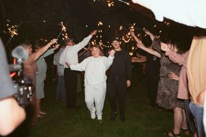 Guests dancing at an outdoor evening wedding reception illuminated by string lights.
