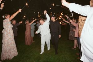 People dancing and celebrating at an outdoor nighttime party with sparklers creating a festive atmosphere.