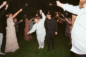 Wedding guests dance with sparklers during an outdoor nighttime celebration.