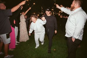 Wedding guests dance together on a dark dance floor during an evening reception celebration.