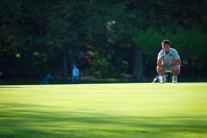 A golfer takes a shot from the fairway at a lush green golf course during a sunny day.