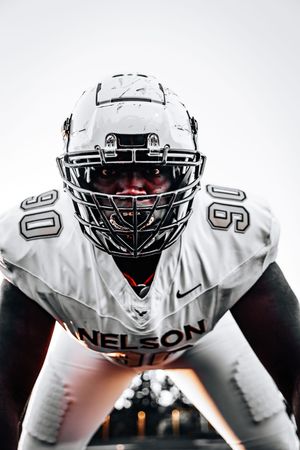 Close-up of football player in white uniform with white helmet in ready position.