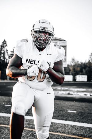 Black and white photo of a football player in white Nike uniform with Nelson written on jersey running with the ball.
