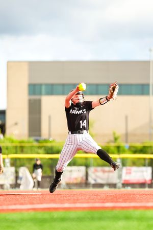 Baseball player leaps high in the air to make a diving catch on the field, displaying impressive athletic skill and timing.