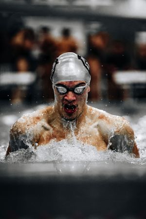 A swimmer performs butterfly stroke technique in the pool creating dynamic splashes during competition.