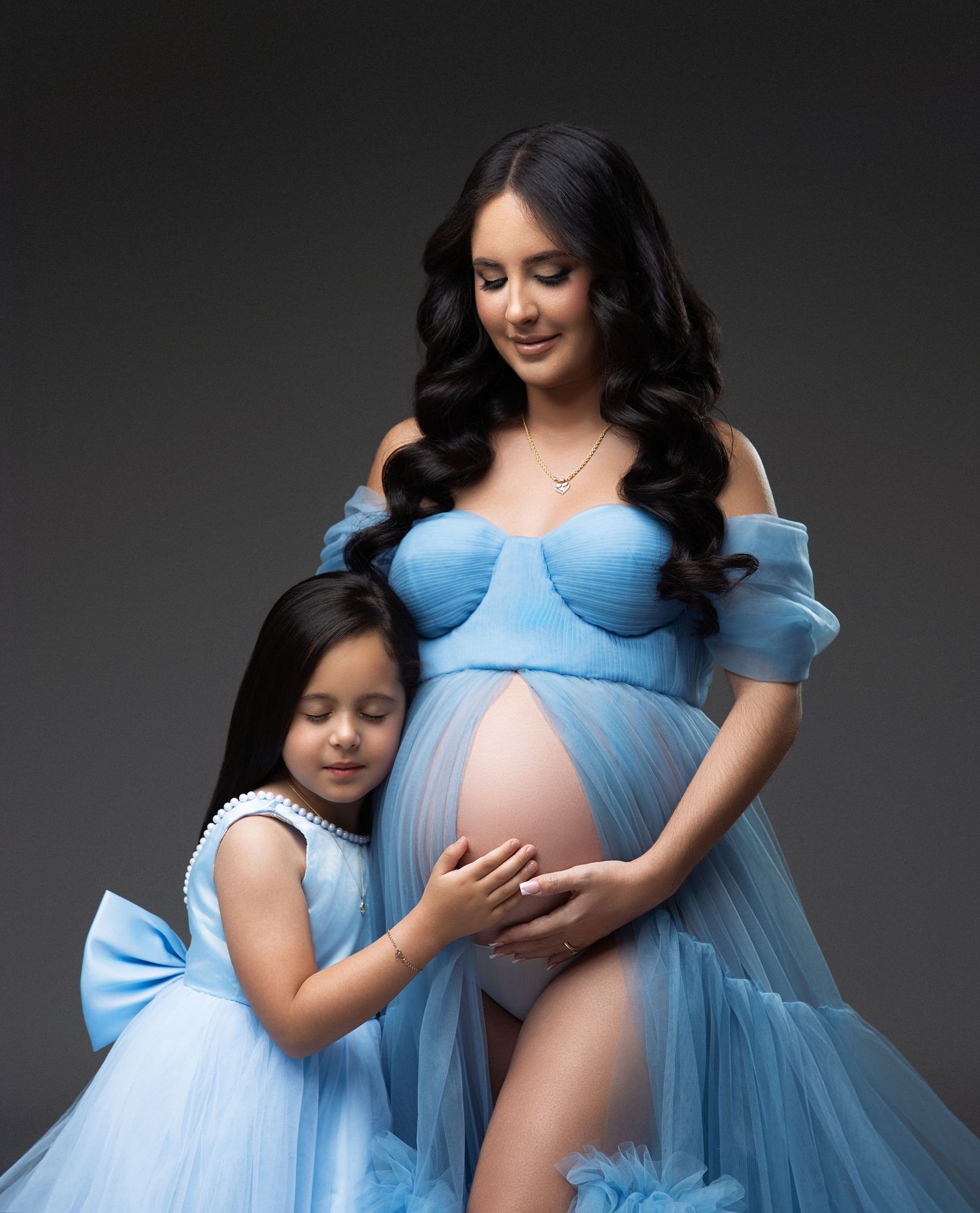 A person in a light blue lingerie set poses elegantly with flowing tulle fabric in a studio setting.