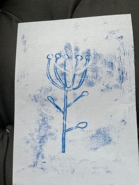A series of blue monotype prints showing stamped tree designs with delicate branches and white backgrounds.