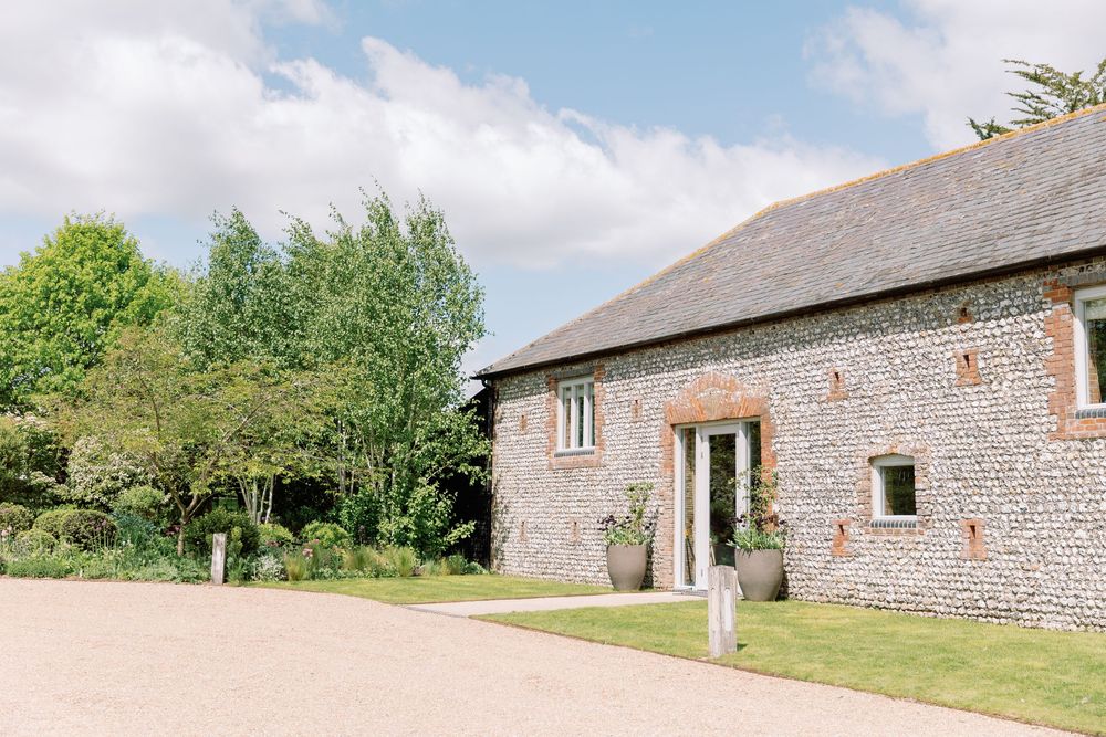 Panoramic exterior view of stone barn conversions with brick details in a rural countryside setting.