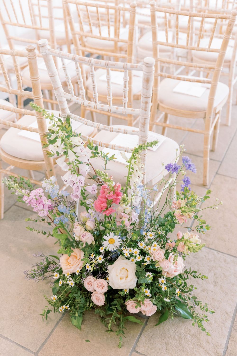 Beautiful floral aisle decorations featuring pink, purple, and white blooms with greenery at a wedding ceremony.