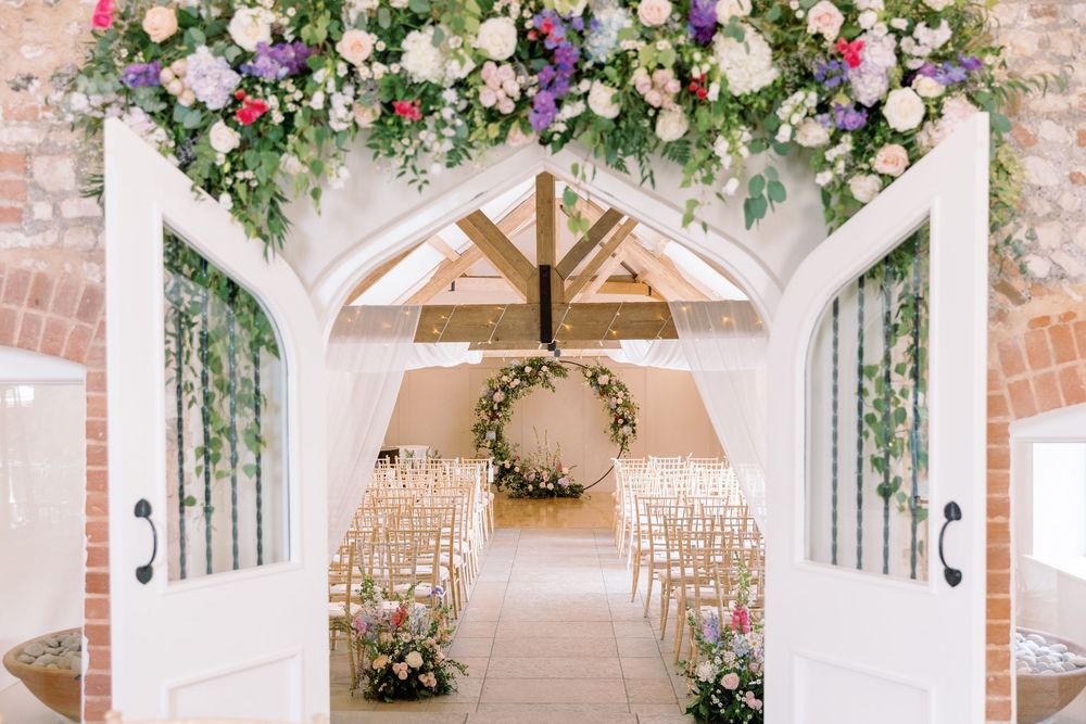 Wedding ceremony space with white beams and floral arrangements in pink and white adorning the arch.