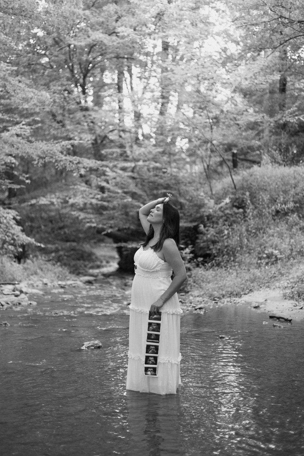 A sequence of black and white photos shows a person in a white dress standing by a stream in a wooded setting.