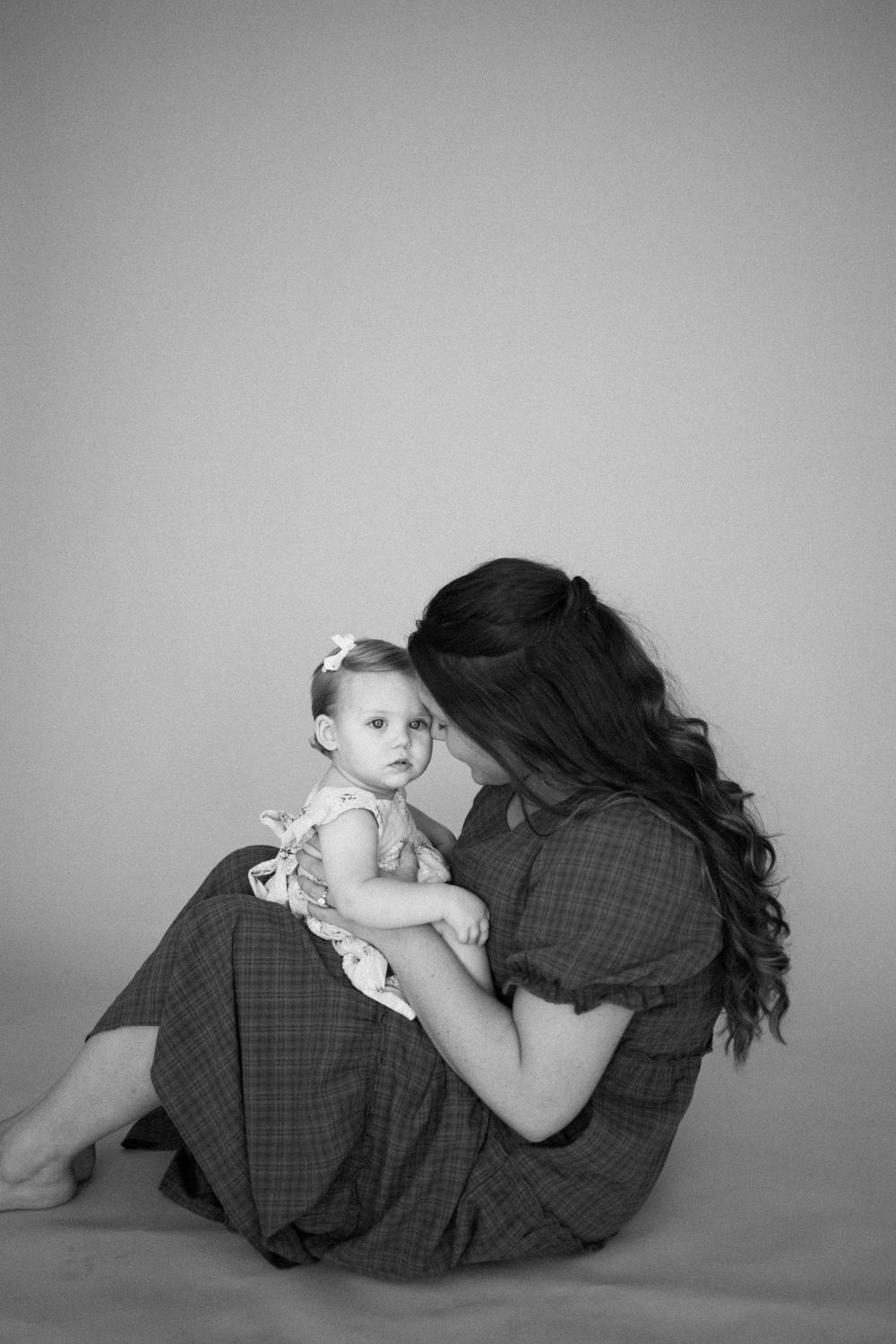 A series of black and white photographs showing a tender moment between parent and baby in curled up poses.