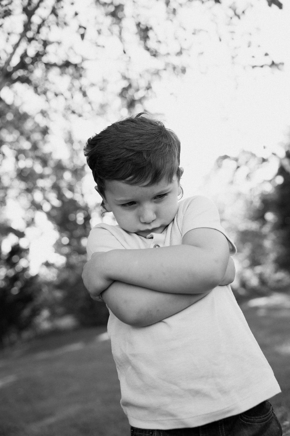 Black and white photo series showing a young child in a white shirt dabbing their face into their elbow.