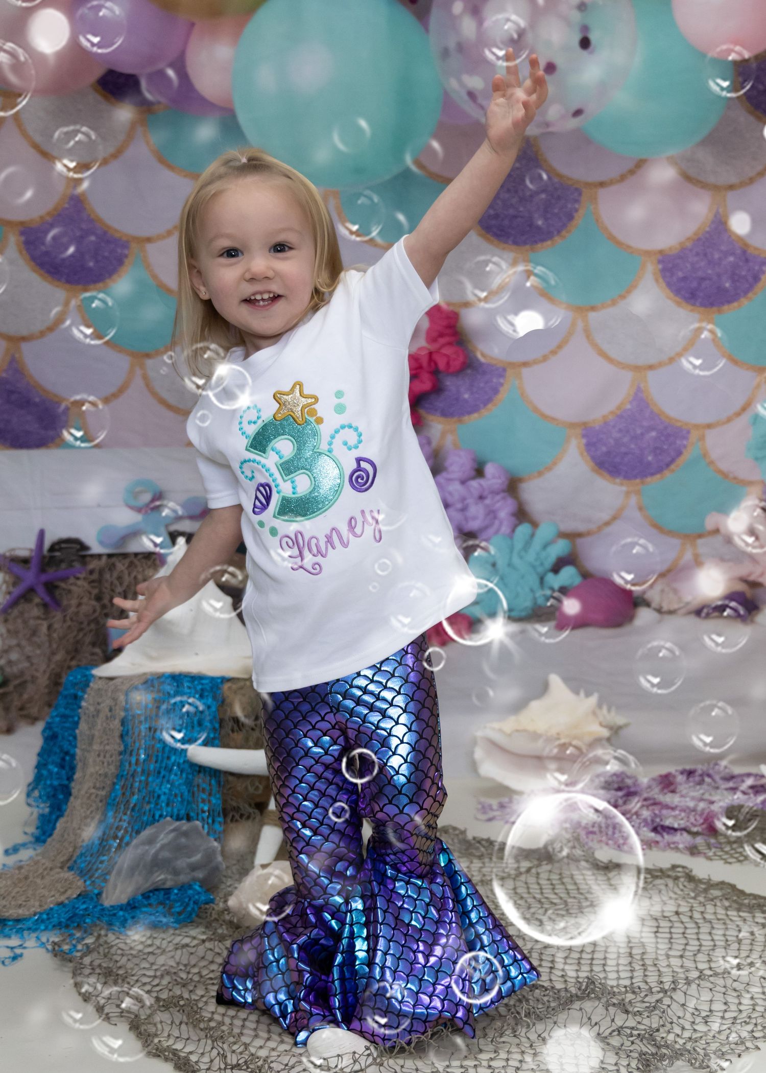 A magical mermaid-themed celebration with bubbles floating among turquoise and pink balloons against a shimmery scaled backdrop.