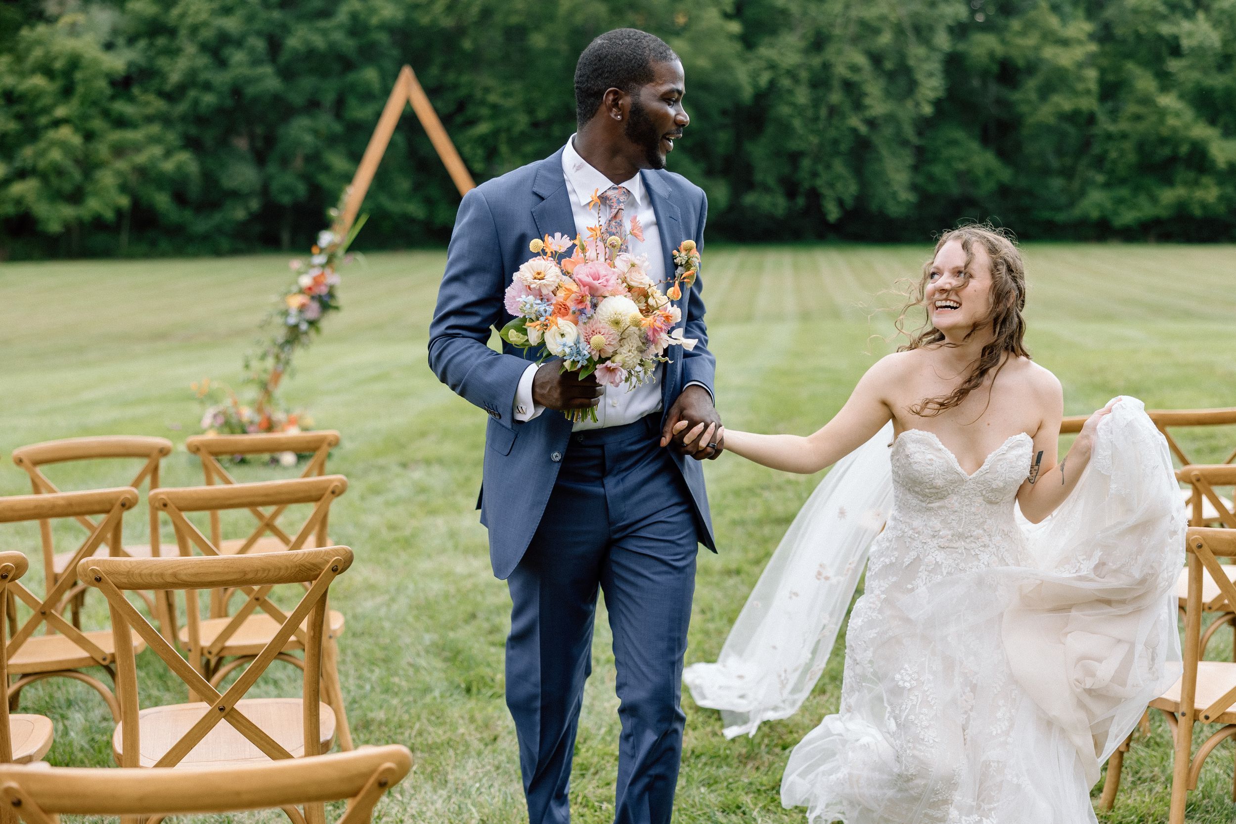 A joyful candid moment between newlyweds on their wedding day in an outdoor garden ceremony setting.
