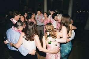 Group of wedding guests huddled in circle during reception dance party.