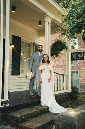 Bride and groom posing on the porch steps of a charming cottage venue on their wedding day.
