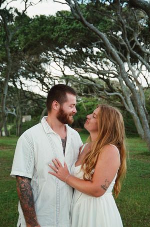A couple shares joyful moments in a lush green outdoor setting during their photo session.