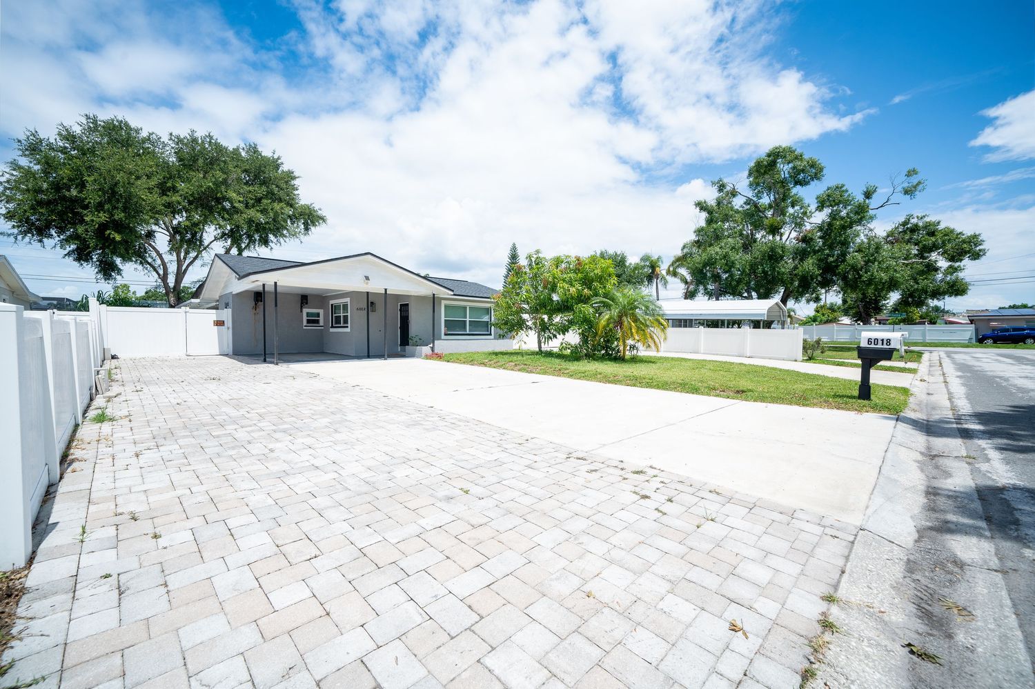 A panoramic view of several mobile homes in a sunny residential community with paved driveways and blue skies.