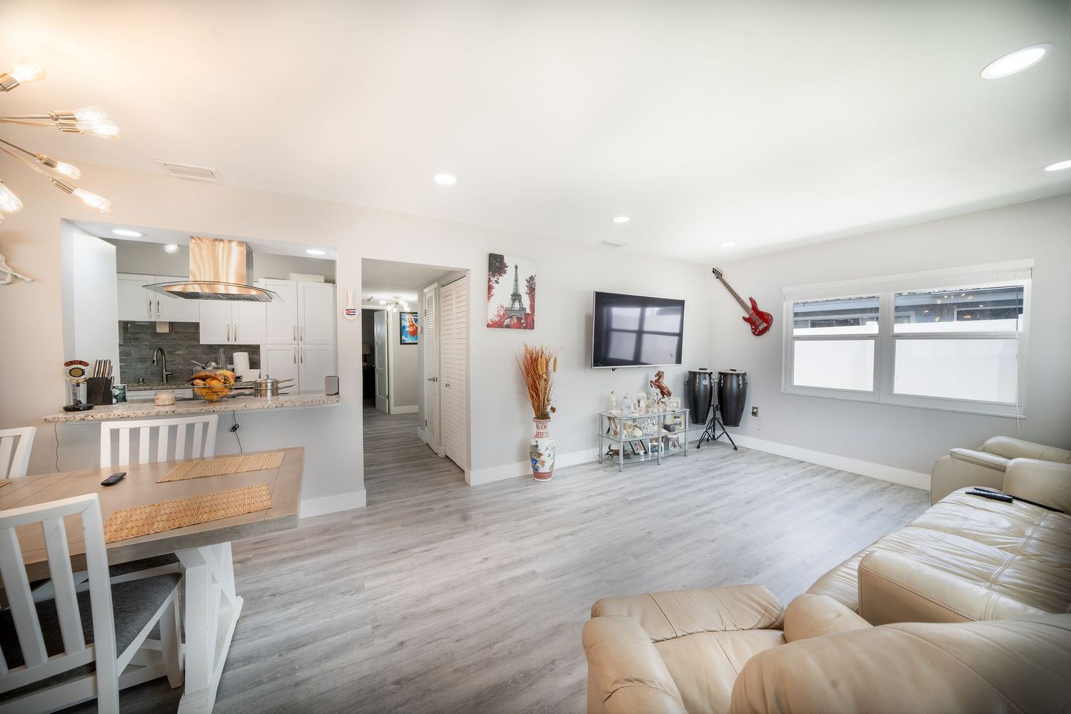 Modern apartment interior with light gray vinyl flooring, white walls and natural lighting showcasing an open concept design.