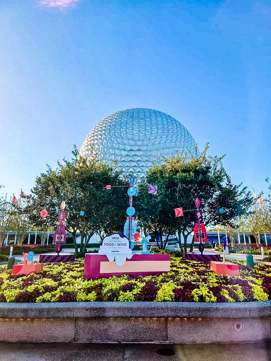 Spaceship Earth at EPCOT with festival decorations and landscaping in the foreground.