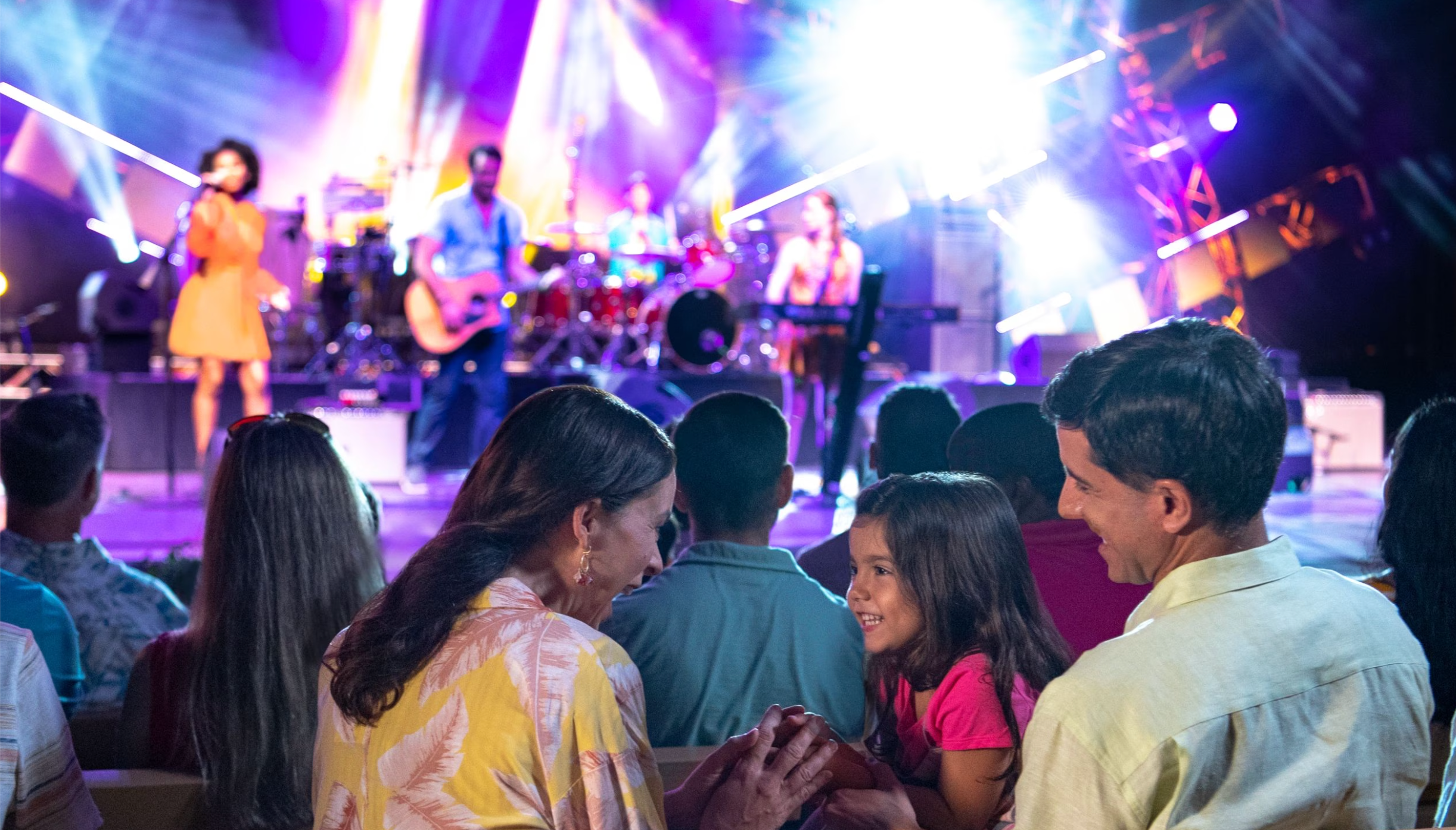Concert crowd enjoying live music performance with colorful stage lighting effects.