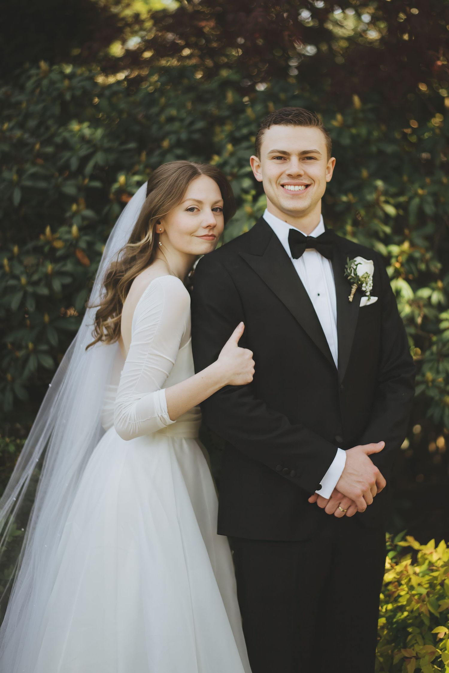 A romantic wedding photo series showing elegant couple in formal attire posing together outdoors with greenery in background.