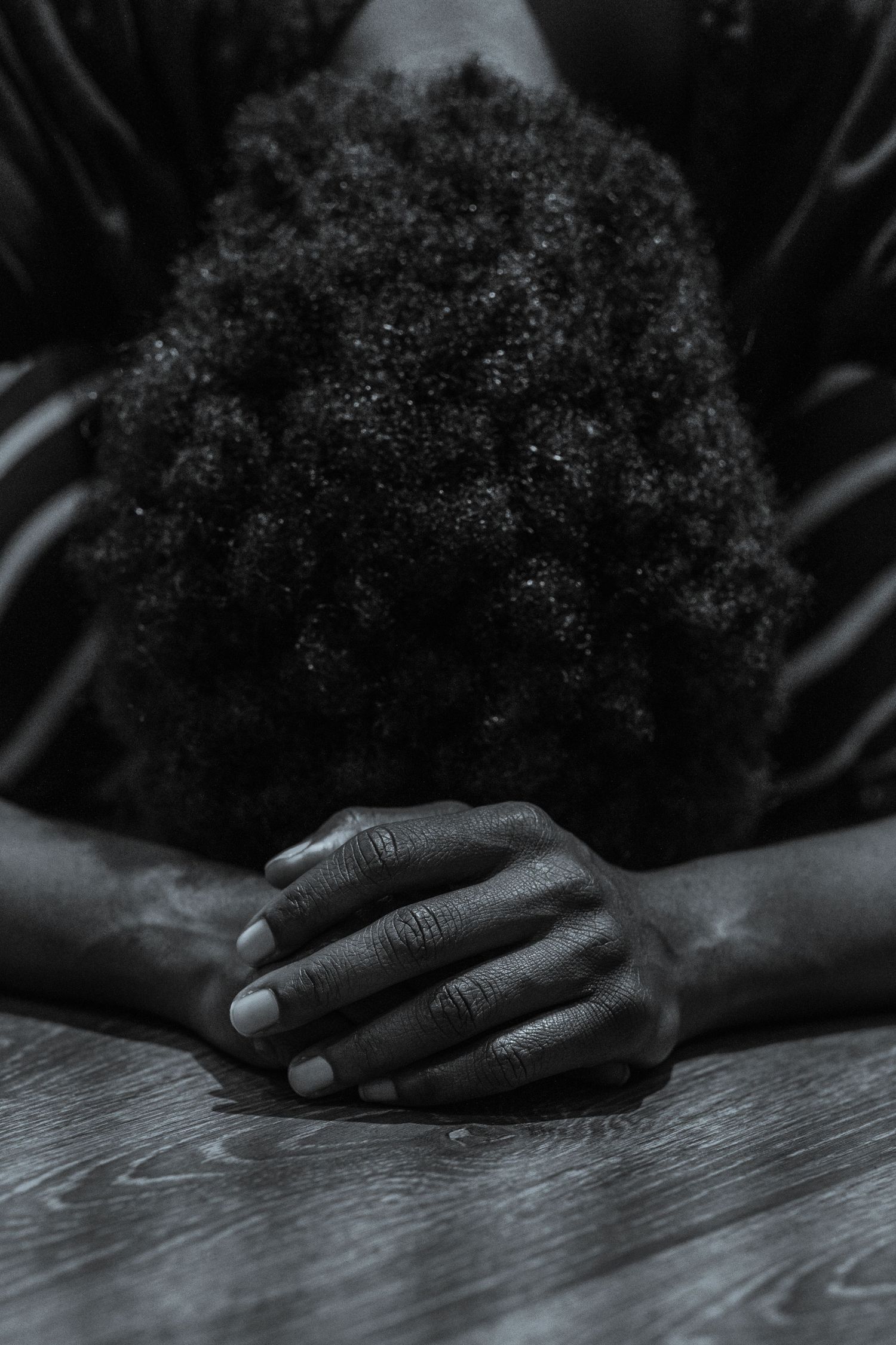 A black and white photo series shows someone praying with their hands clasped in dim lighting.