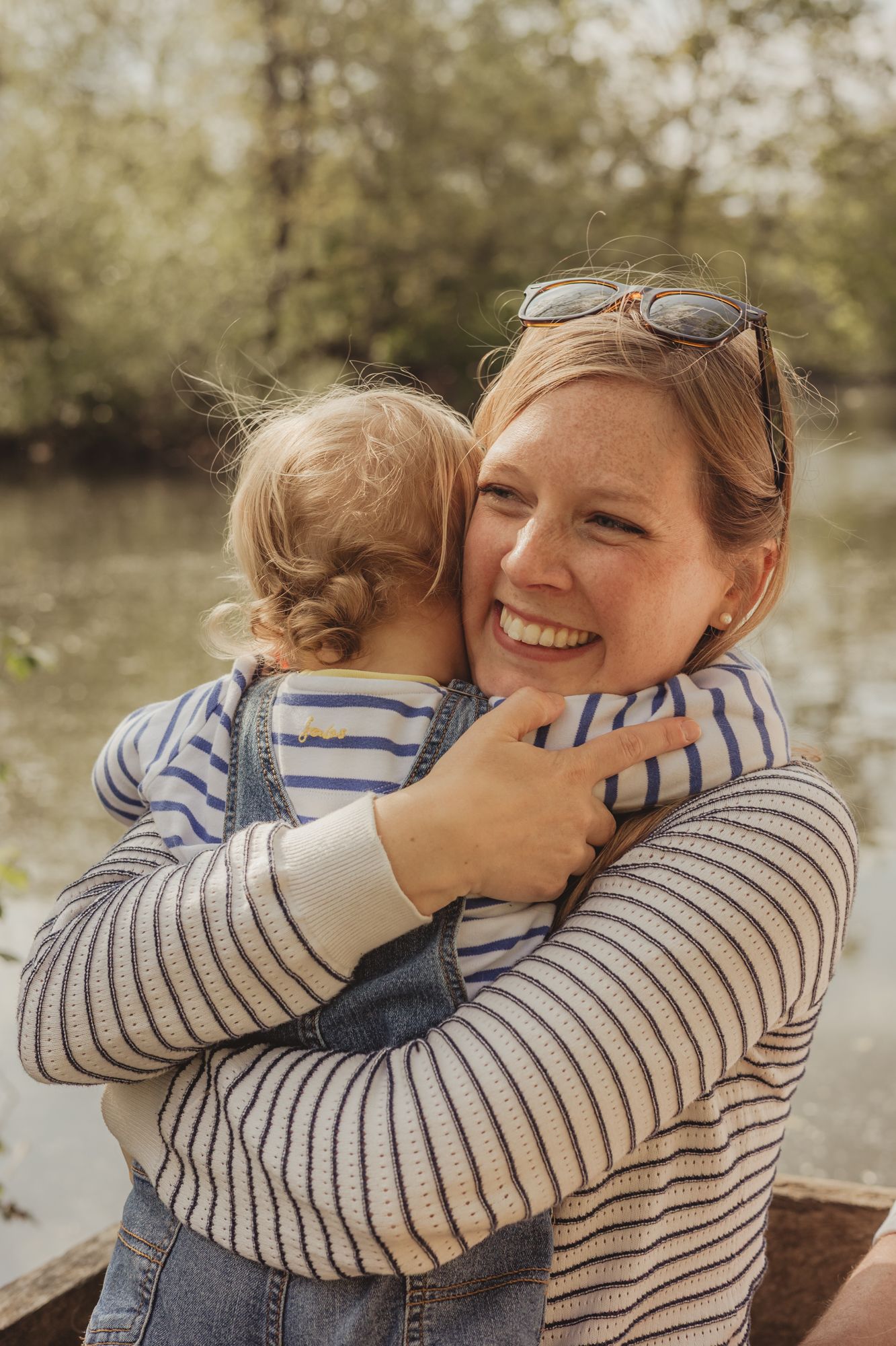 A tender moment captured in a series of photos showing a parent and child embracing in matching striped sweaters outdoors.