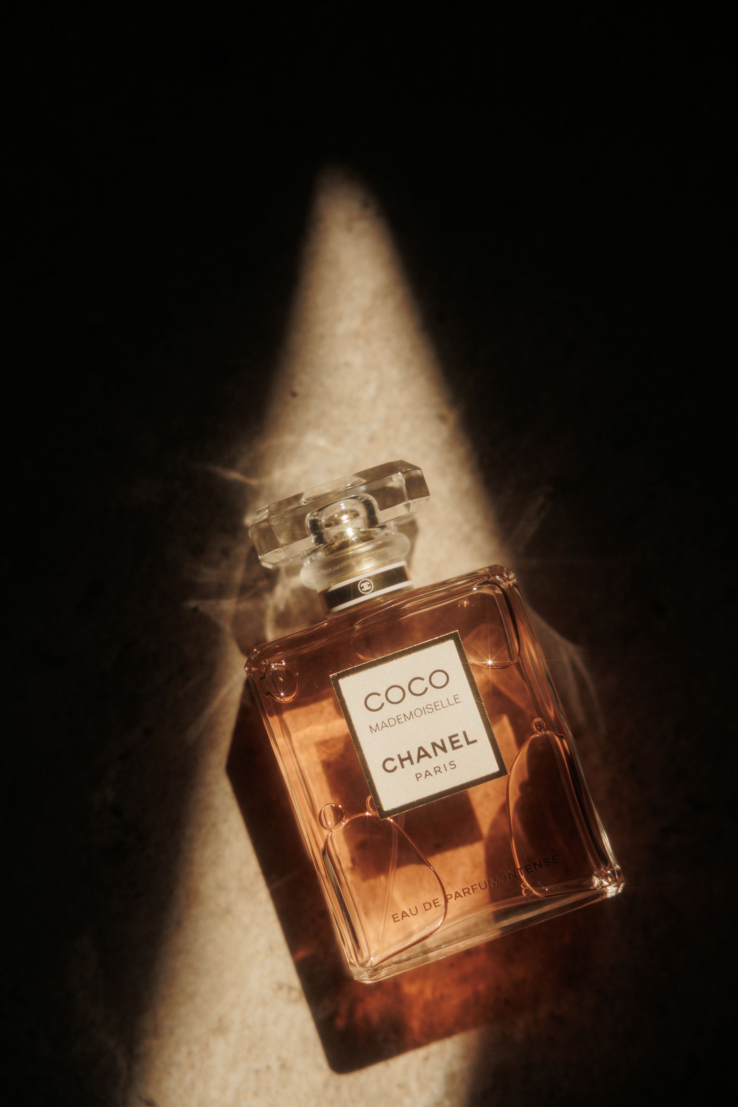 Artistic close-up shots of Chanel Coco perfume bottles at different angles with dramatic lighting and shadows.