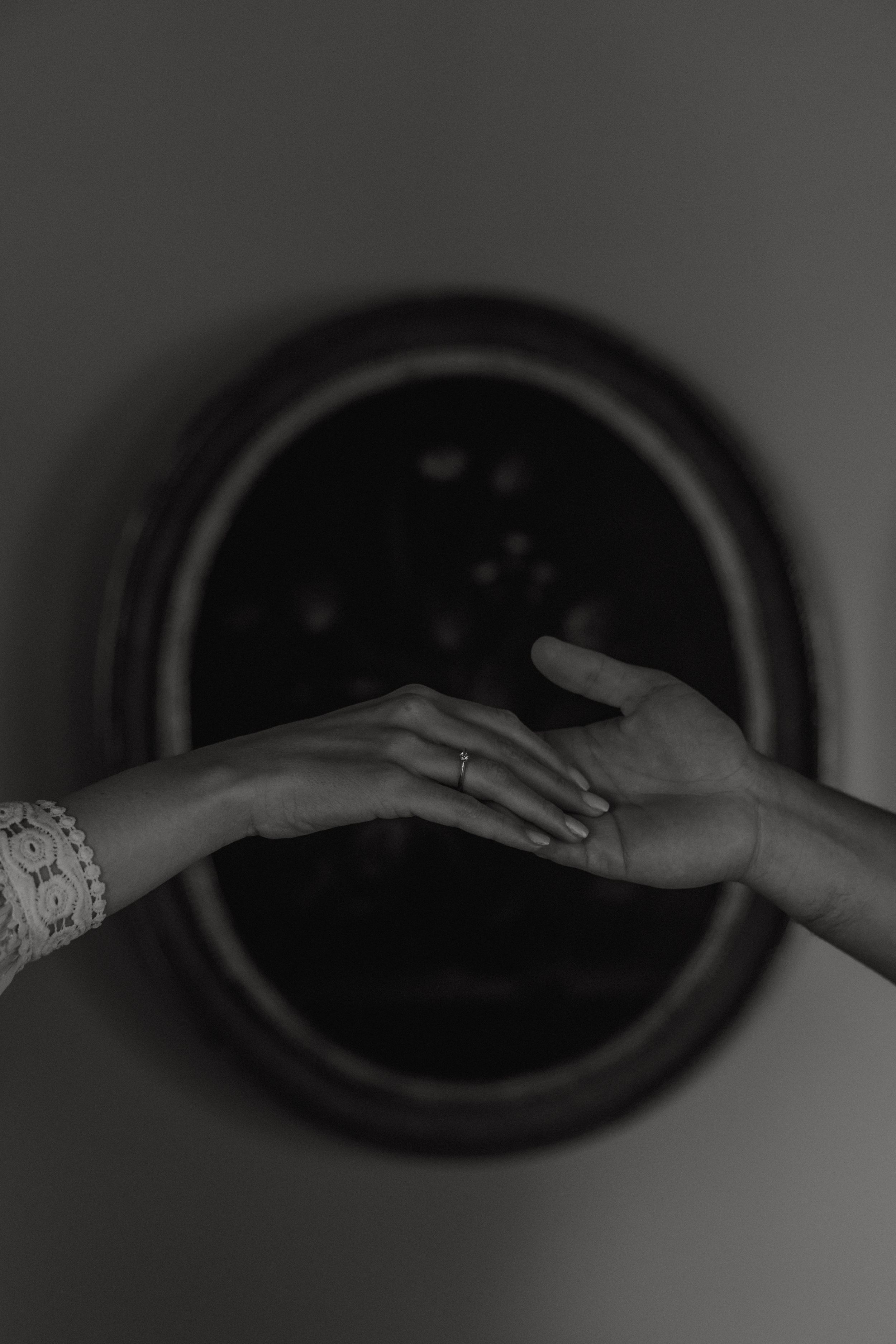 Black and white artistic close-up photo of two hands reaching towards each other, with one wearing an elegant bracelet.