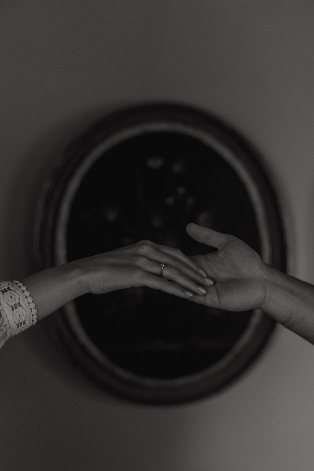 Black and white artistic close-up photo of two hands reaching towards each other, with one wearing an elegant bracelet.