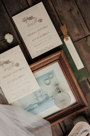 Wedding invitation suite and rings displayed on rustic wooden table setting with blue and white watercolor designs.