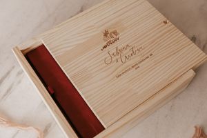 An elegant light wooden box with engraved text and red velvet lining for wedding photos or gifts.