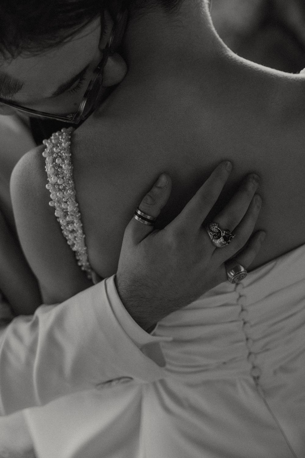 A close-up black and white photo of someone wearing pearl earrings and a white garment.